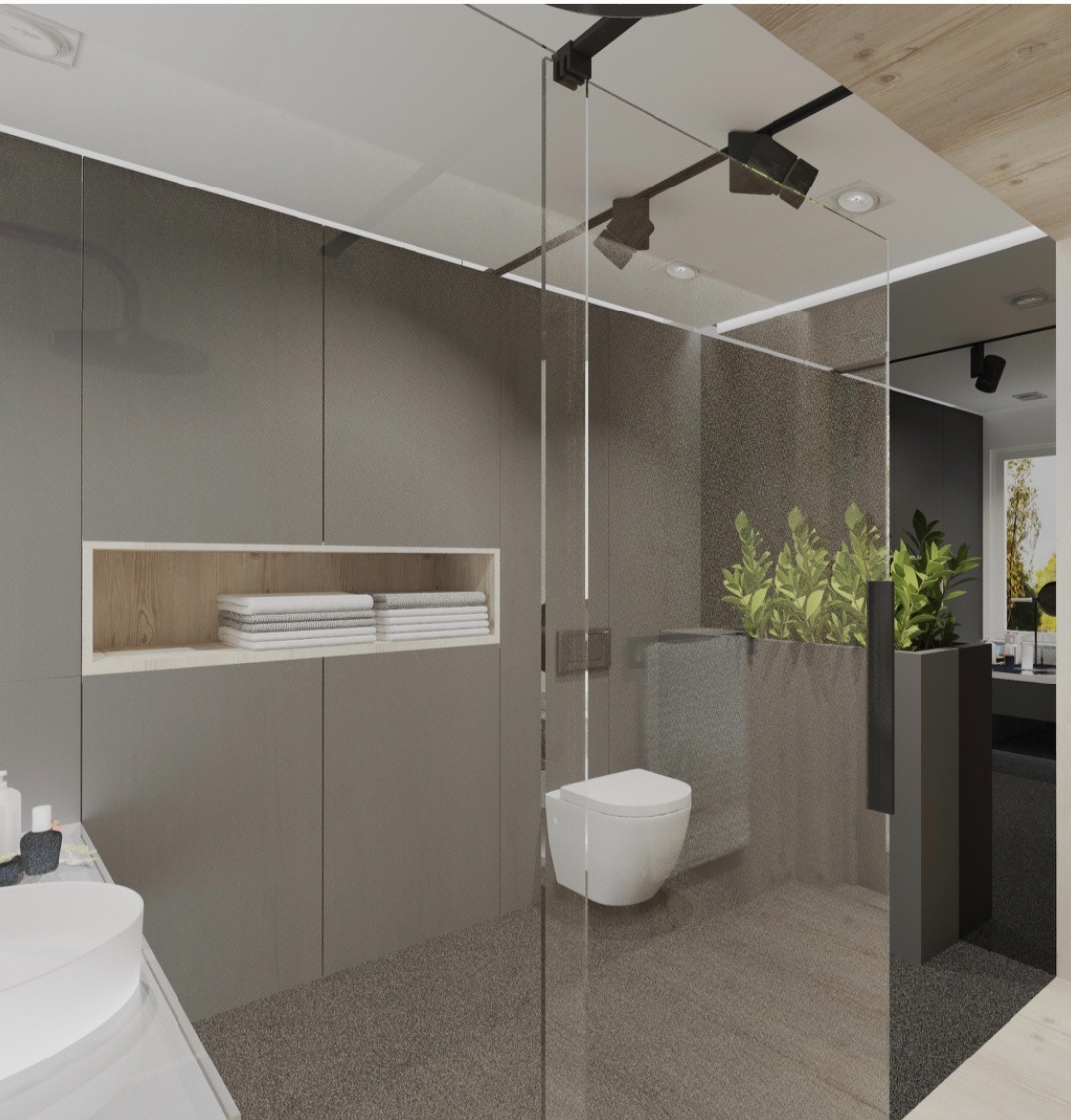 Minimalistyczna łazienka z szarą zabudową, wnęką z ręcznikami, toaletą wiszącą i przeszkloną kabiną prysznicową z roślinami w donicy.