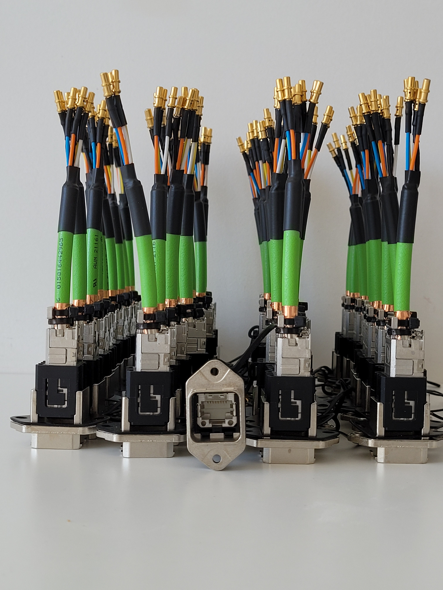 Zestaw zmontowanych złączy telekomunikacyjnych z kolorowymi przewodami, przygotowanych przez instalatora z Krakowa. Widoczne zielone osłonki kabli i pozłacane końcówki.