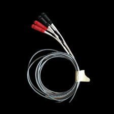 Kabel telekomunikacyjny z trzema przewodami zakończonymi czerwonymi i czarnymi wtykami, zwinięty w okrąg, na czarnym tle.