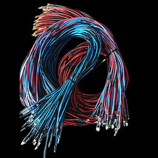 Splot kolorowych kabli (czerwone, niebieskie, białe) związanych czarnymi opaskami zaciskowymi na czarnym tle.