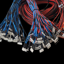 Zestaw wiązek przewodów elektrycznych w kolorach niebieskim, czarnym i czerwonym, zakończonych białymi złączami, na czarnym tle.