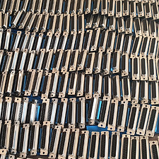 Rząd metalowych złączy DB25 ułożonych równolegle, widoczne czarne piny wewnątrz obudów, równomierne oświetlenie.