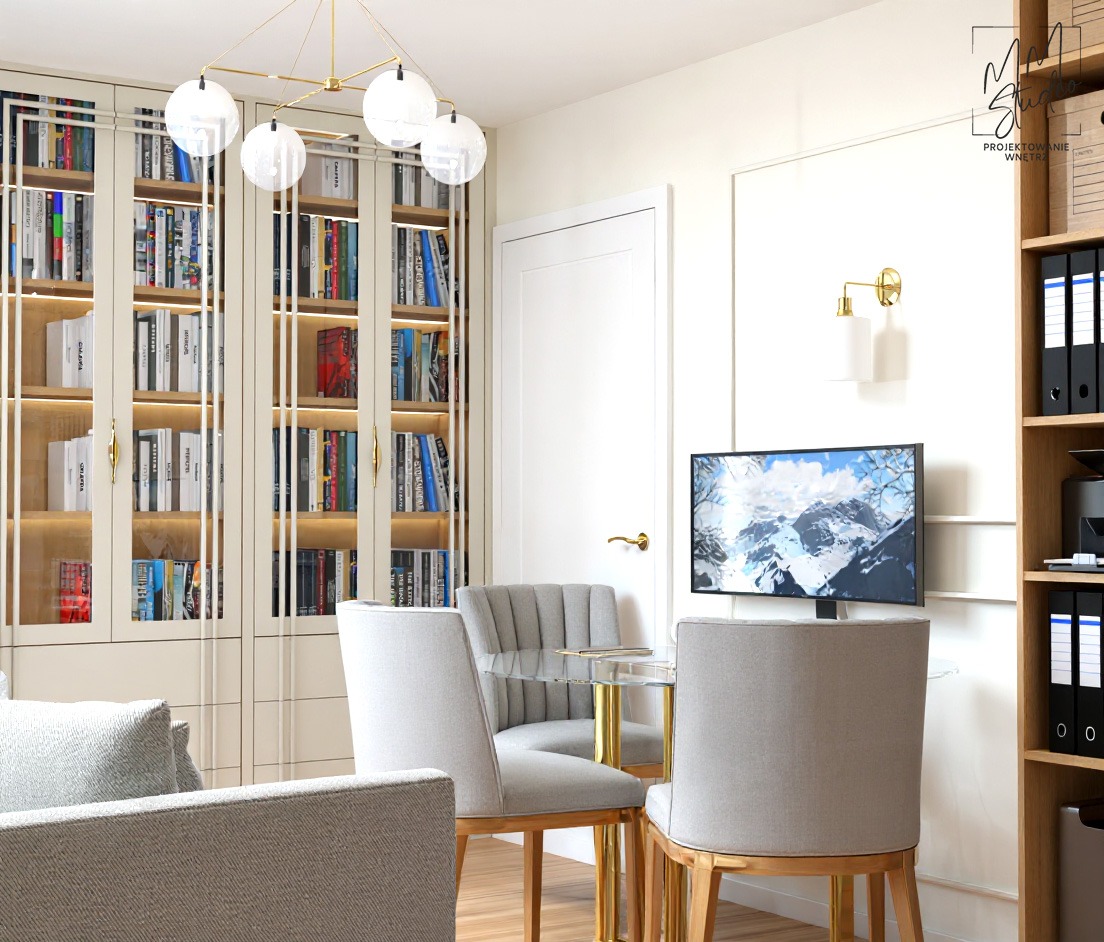 Elegancki pokój z przeszkloną biblioteczką, szarymi krzesłami przy szklanym stole na złotych nogach, lampą ścienną i telewizorem z górskim krajobrazem.
