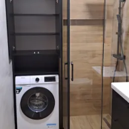 Nowoczesna łazienka z kabiną prysznicową typu walk-in z czarnymi ramami, szafką nad pralką i drewnopodobnymi płytkami na ścianach i podłodze.