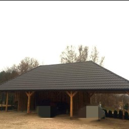 Paweł Statuch BuildKraft - Zadaszenie na dwa samochody z brązową blachą trapezową, drewniana konstrukcja z widocznymi belkami, w tle drzewa bez liści.