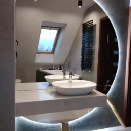 Nowoczesna łazienka z okrągłym lustrem podświetlanym LED, dwie umywalki nablatowe na szarym blacie, widok na wannę i okno dachowe w odbiciu lustra.