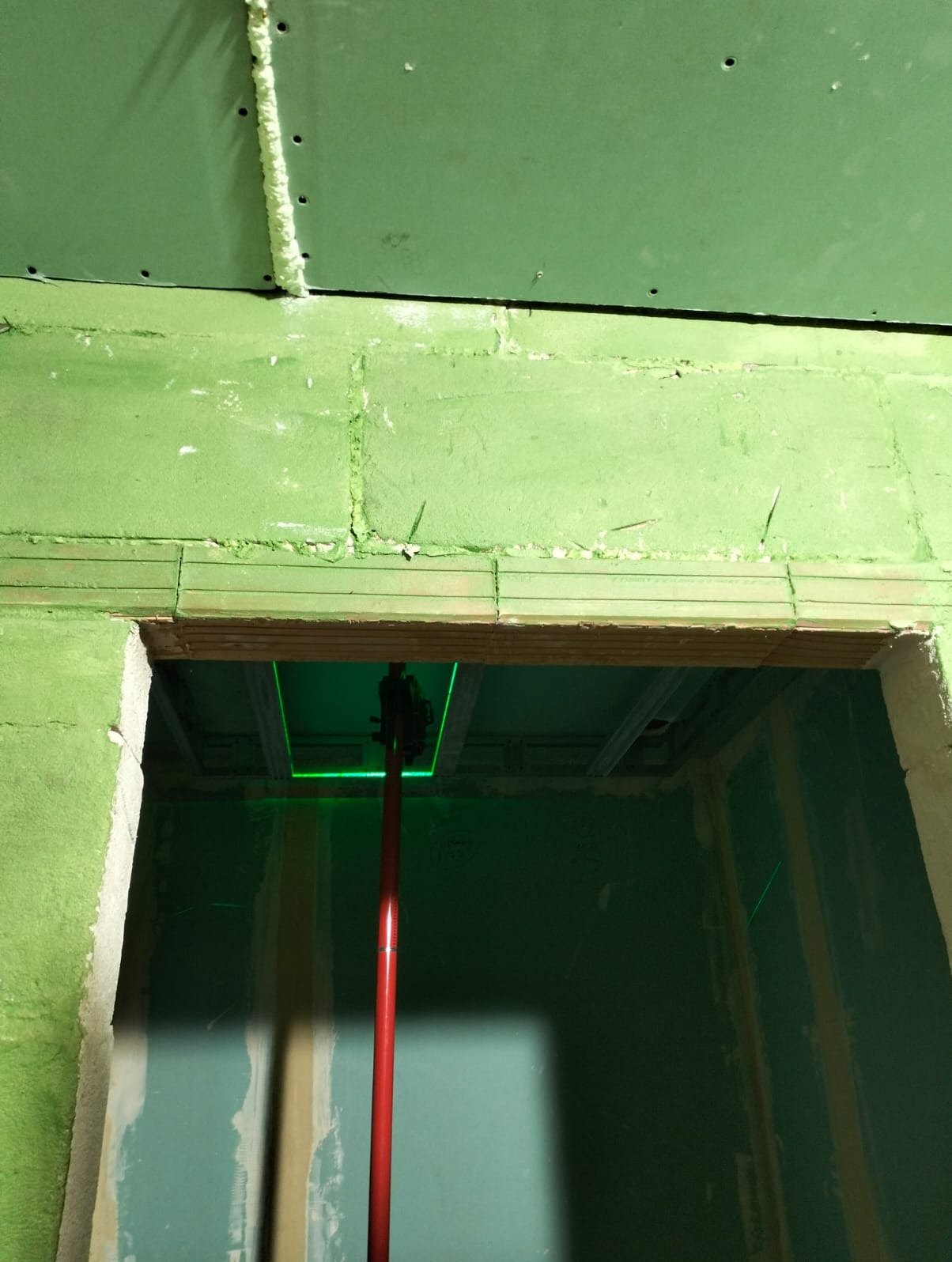 Montaż sufitu podwieszanego w Chełmie. Widoczny laser krzyżowy, płyty gipsowe i konstrukcja metalowa. Prace wykończeniowe w trakcie realizacji.