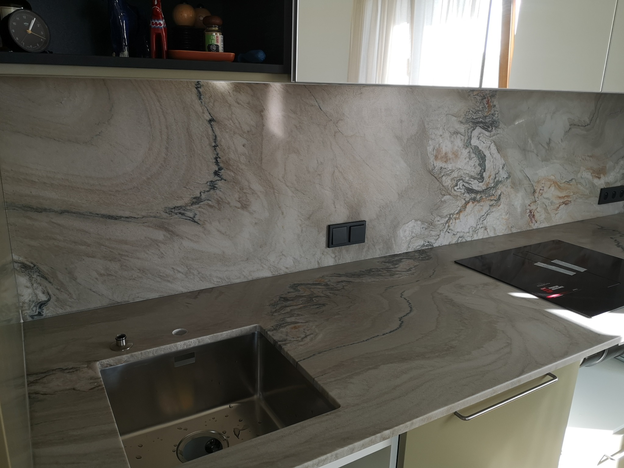 Kamienny blat kuchenny z wyciętym otworem na zlew i płytą indukcyjną, wzór przypominający marmur, elegancki i nowoczesny design.