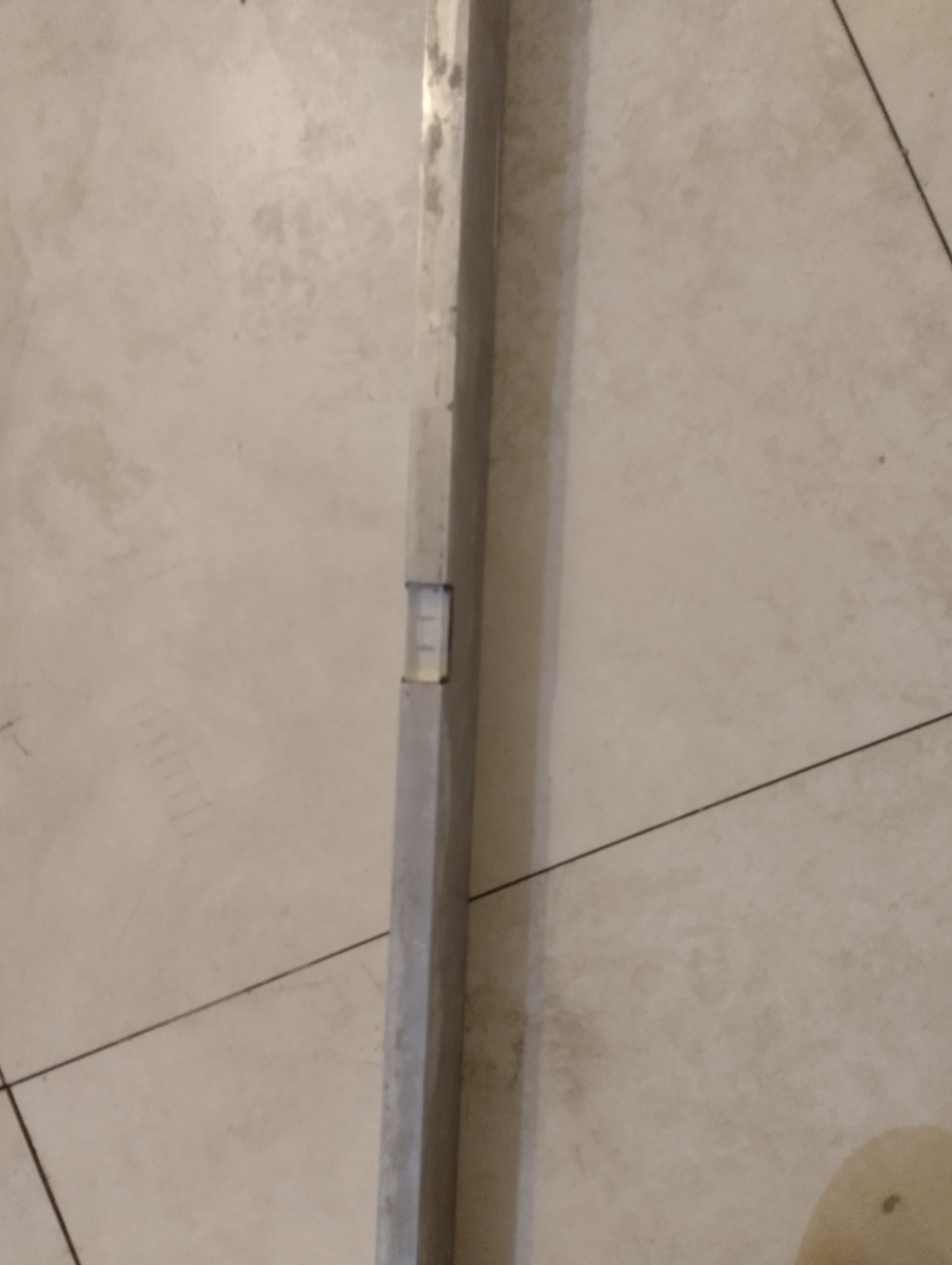 Poziomica w pionie, przyłożona do ściany pokrytej gładzią, sprawdzająca jej pionowość.