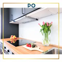 Nowoczesna kuchnia z drewnianym blatem, czarną płytą indukcyjną, bukietem różowych tulipanów w szklanym wazonie, truskawkami i szparagami na desce do krojenia, oraz szarym okapem.