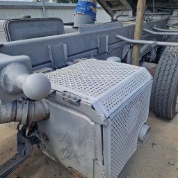 Fresz Natalia Loc - Szare elementy podwozia ciężarówki po piaskowaniu i malowaniu, widoczne detale konstrukcji i opona. Oznakowanie Mercedes na boku.