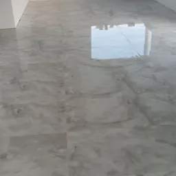 Błyszcząca, marmurkowa podłoga z płytek w nowym, jasnym pomieszczeniu z oknem, przez które widać pola.