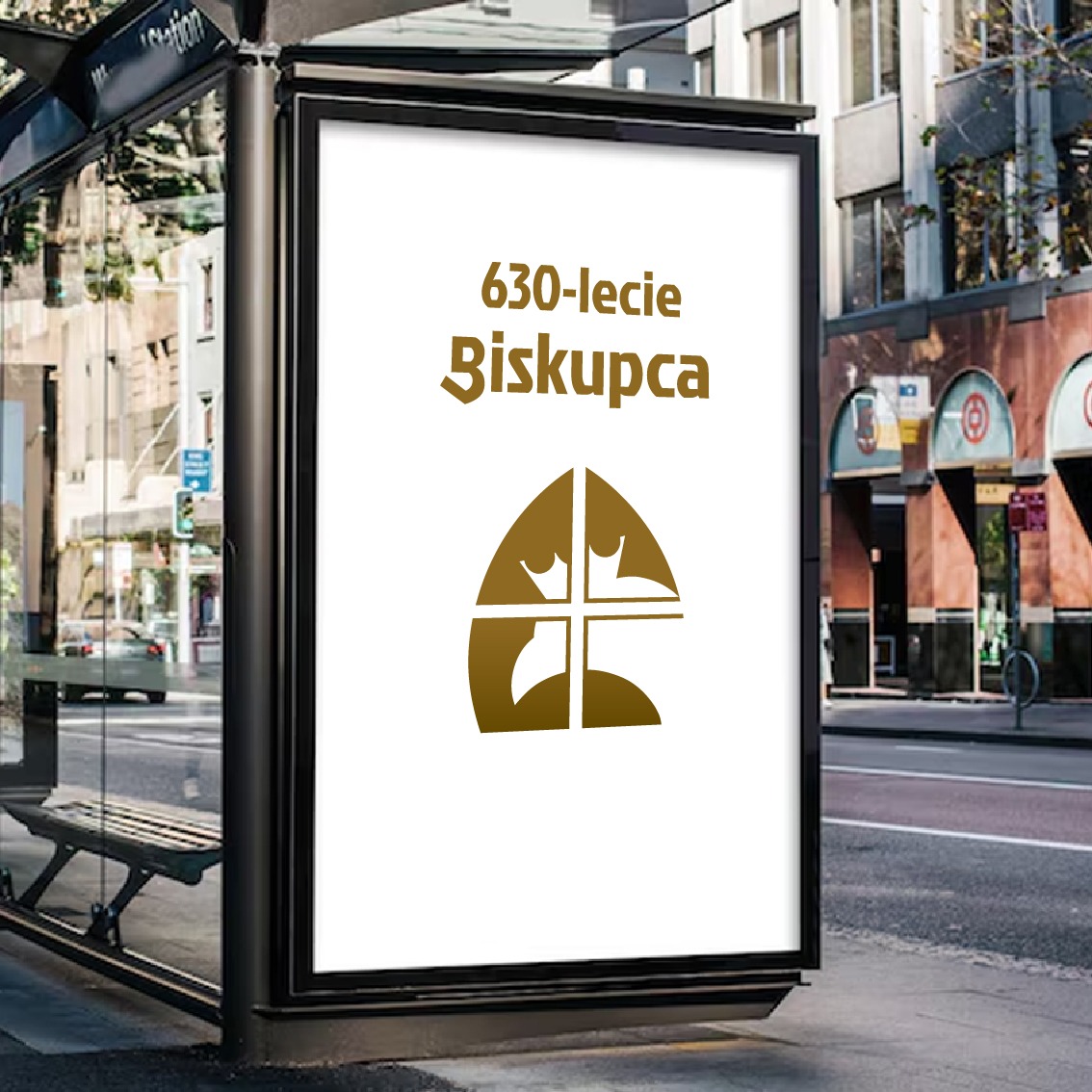 Billboard na przystanku autobusowym promujący 630-lecie Biskupca z charakterystycznym logo miasta w kolorze złotym.