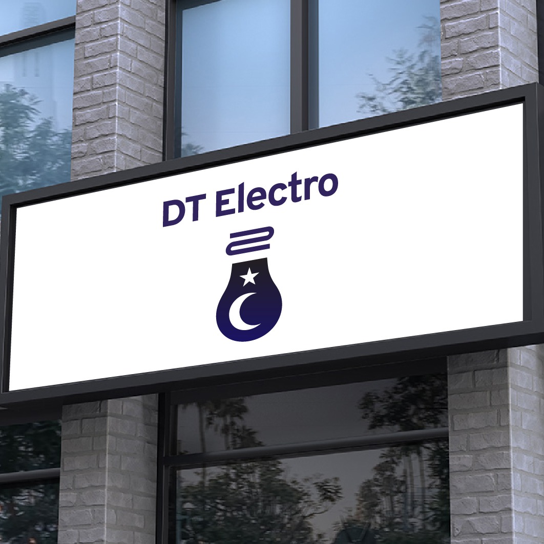 Szyld reklamowy z logo 'DT Electro' przedstawiającym żarówkę z księżycem i gwiazdą, zamontowany na fasadzie budynku z cegły.