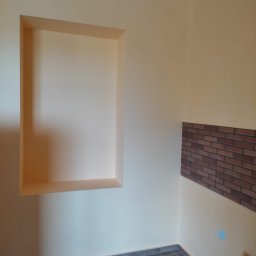 LEPARD - Wnęka w ścianie pomalowanej na kremowo, z fragmentem ściany wyłożonym cegiełkami i panelami podłogowymi w Bydgoszczy.