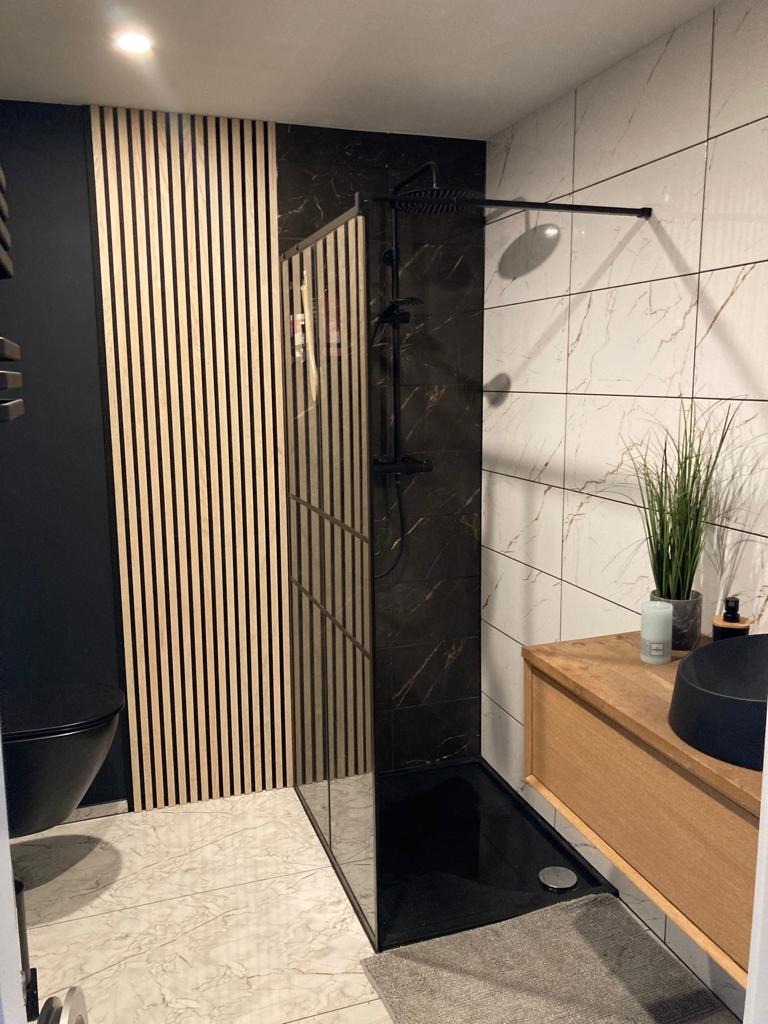 Nowoczesna łazienka w Belfeld z czarną armaturą, kabiną prysznicową typu walk-in z czarnym brodzikiem, drewnianymi lamelami na ścianie i marmurowymi płytkami.