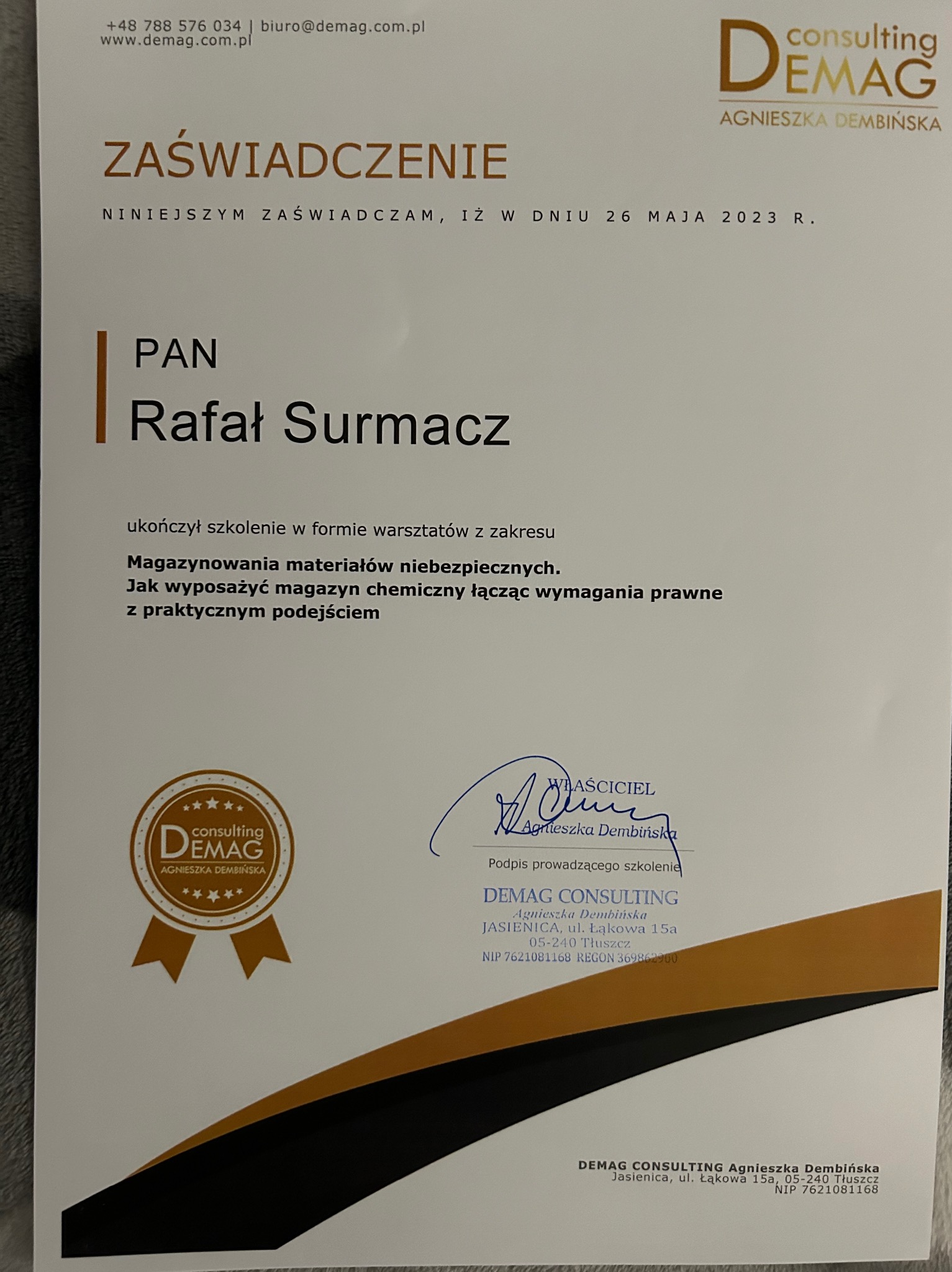 Skan zaświadczenia o ukończeniu szkolenia z zakresu magazynowania materiałów niebezpiecznych, wystawionego przez Demag Consulting dla Rafała Surmacza, z podpisem Agnieszki Dembińskiej.