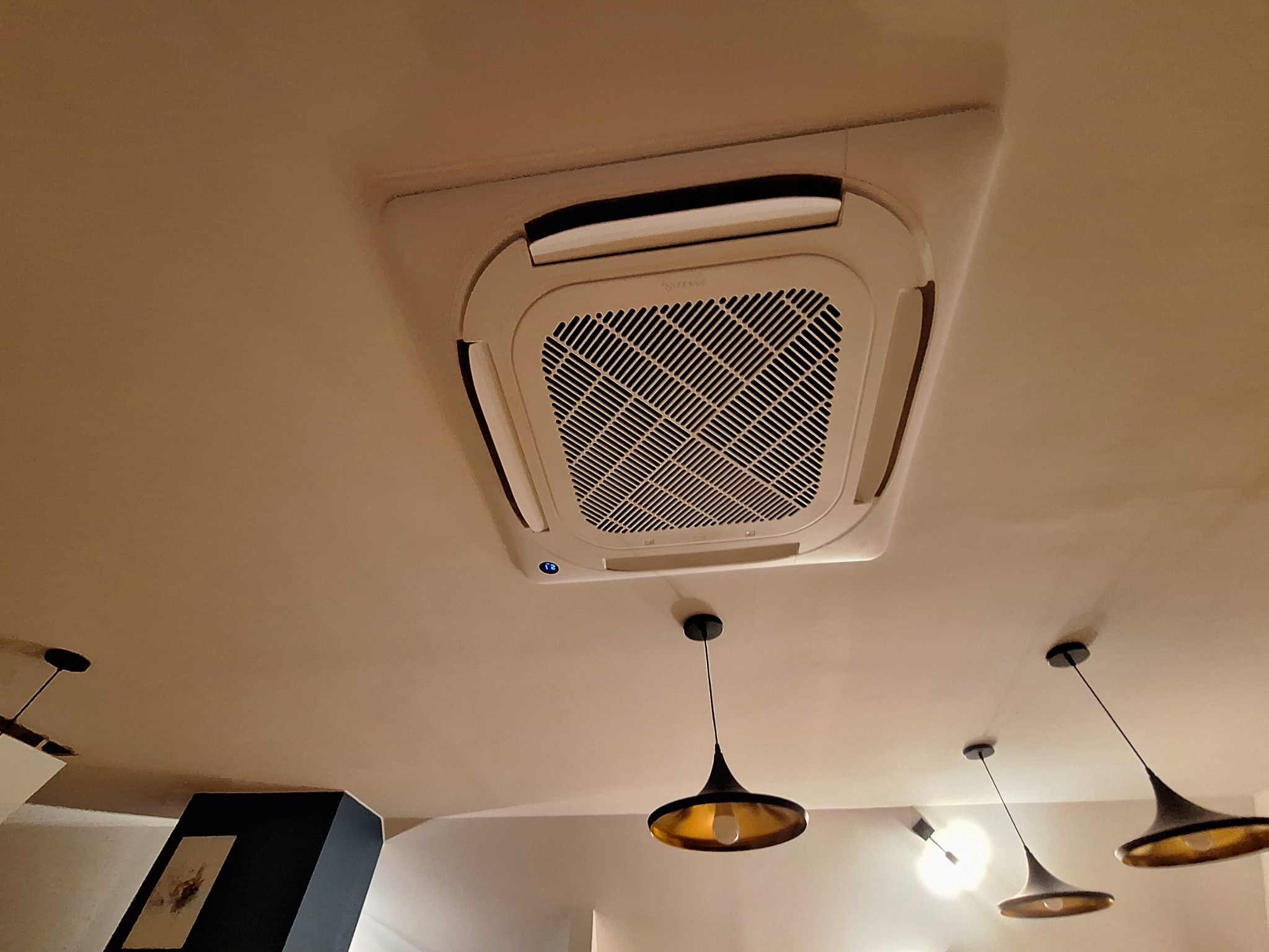 Kasetonowa jednostka klimatyzacyjna zamontowana w suficie w Gdyni, widoczna z perspektywy żyrandoli w stylu retro.