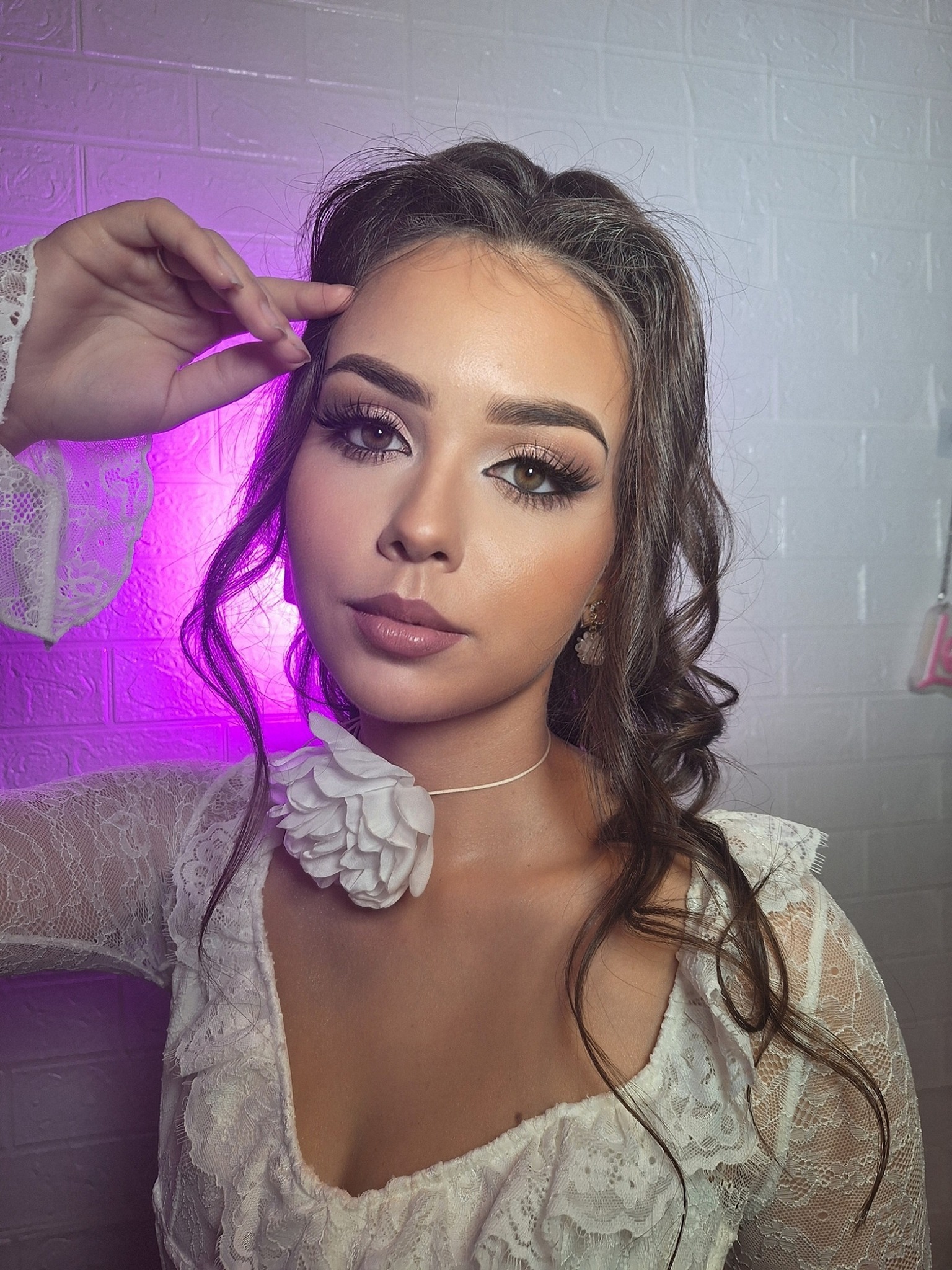 Portret kobiety z profesjonalnym makijażem i kwiatem przy szyi, wykonanym w Wieluniu. Delikatny makijaż oczu i ust, podkreślone rzęsy, biała koronkowa bluzka.