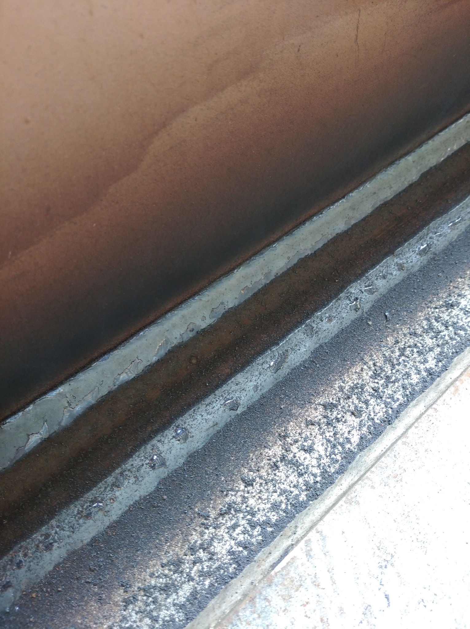 Spoina łącząca dwie metalowe powierzchnie, widoczne ślady po spawaniu i drobne odpryski.