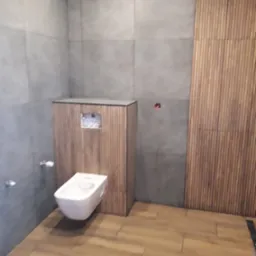 Nowoczesna łazienka z podwieszaną toaletą, szarą glazurą i drewnianymi panelami ściennymi.