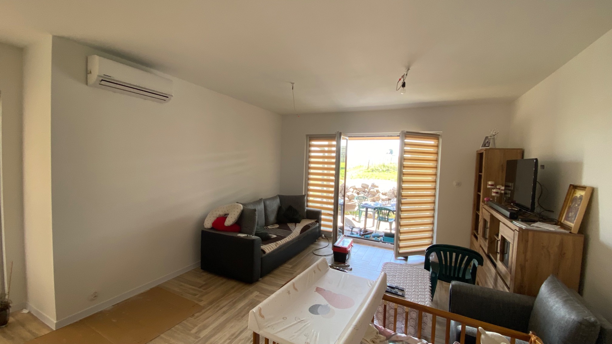 Zamontowany klimatyzator w jasnym salonie w Wieliczce, widoczny narożnik, meble i otwarte drzwi balkonowe na zewnątrz.