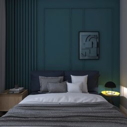 Biuro projektowe DPConcept - Nowoczesna sypialnia z łóżkiem z szarą narzutą w jodełkę, ciemnoniebieską ścianą z ramami, abstrakcyjnym obrazem, lampką nocną z żółtym blatem i zasłonami wpadającymi do pokoju przez okno.