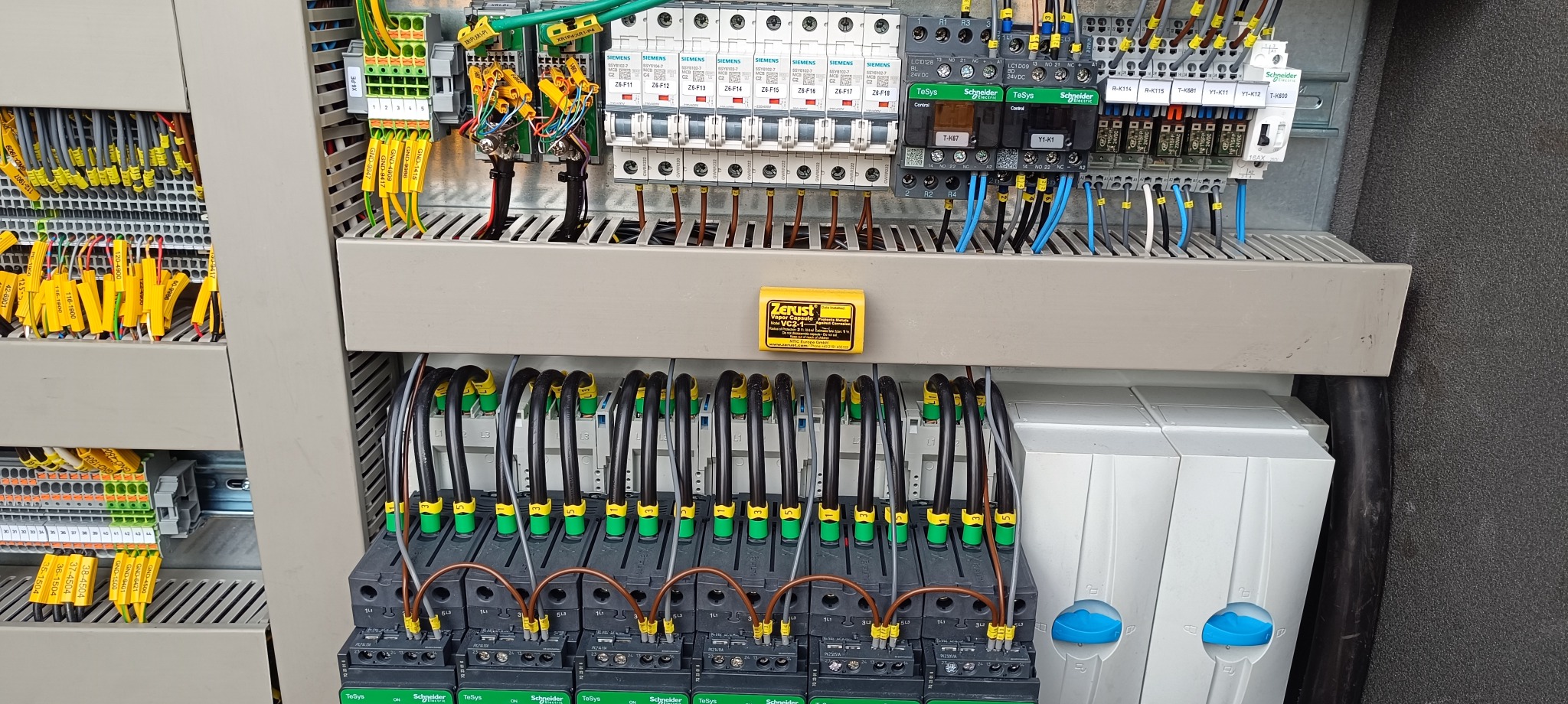 Rozdzielnica elektryczna z widocznymi bezpiecznikami, stycznikami Schneider Electric TeSys, okablowaniem oznaczonym żółtymi etykietami i zabezpieczeniem antykorozyjnym Zerust Vapor Capsule.