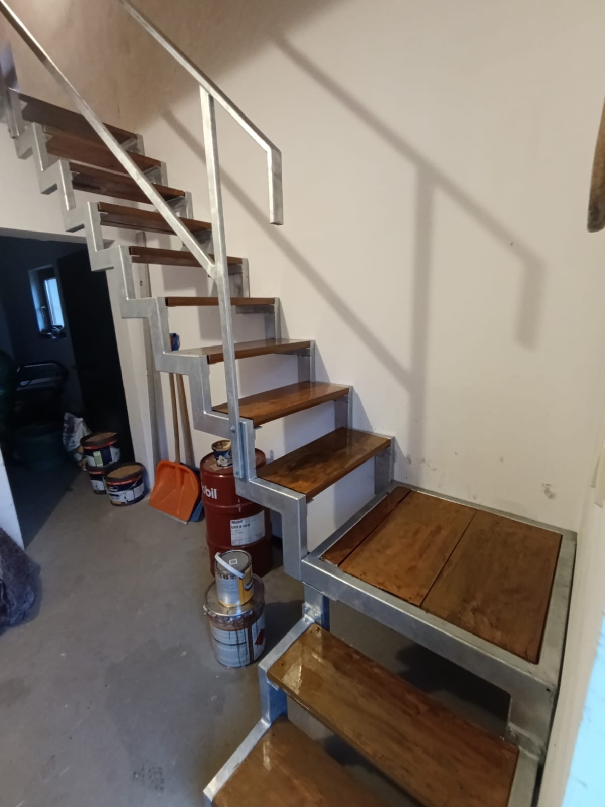 Metalowe schody z drewnianymi stopniami w Czyżowicach, widoczne puszki z farbą i wiadro w tle.