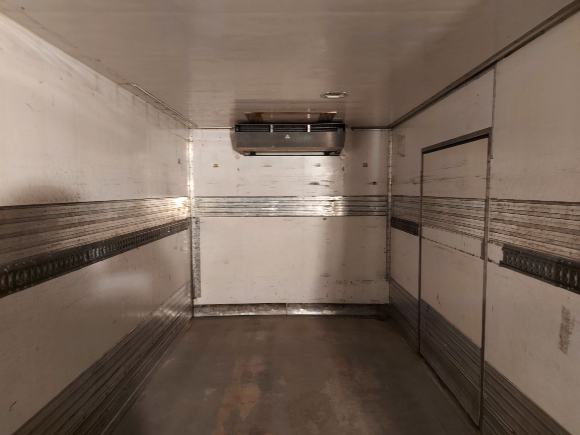Wnętrze pustej, chłodni samochodowej z zamontowanym agregatem chłodniczym pod sufitem, widoczne metalowe listwy mocujące na ścianach.