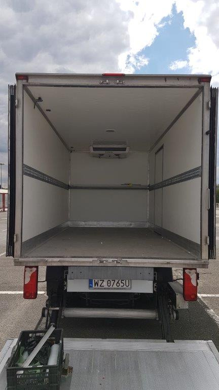 Pusta, klimatyzowana przestrzeń ładunkowa samochodu ciężarowego z otwartymi drzwiami, widoczny numer rejestracyjny i podnośnik załadunkowy.