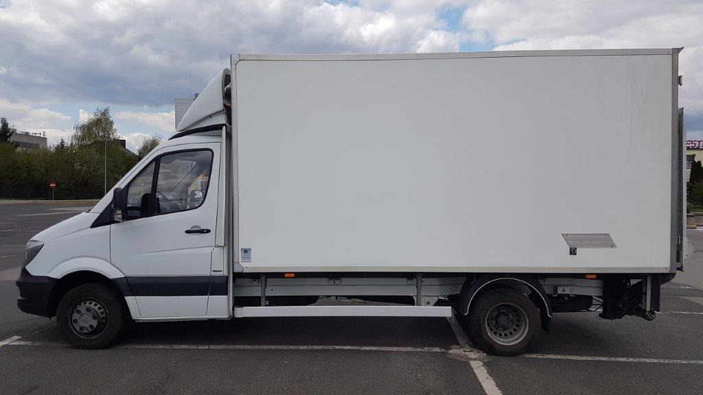 Biały samochód dostawczy typu furgon z zabudową izotermiczną, zaparkowany na parkingu, widok z boku, szare felgi.