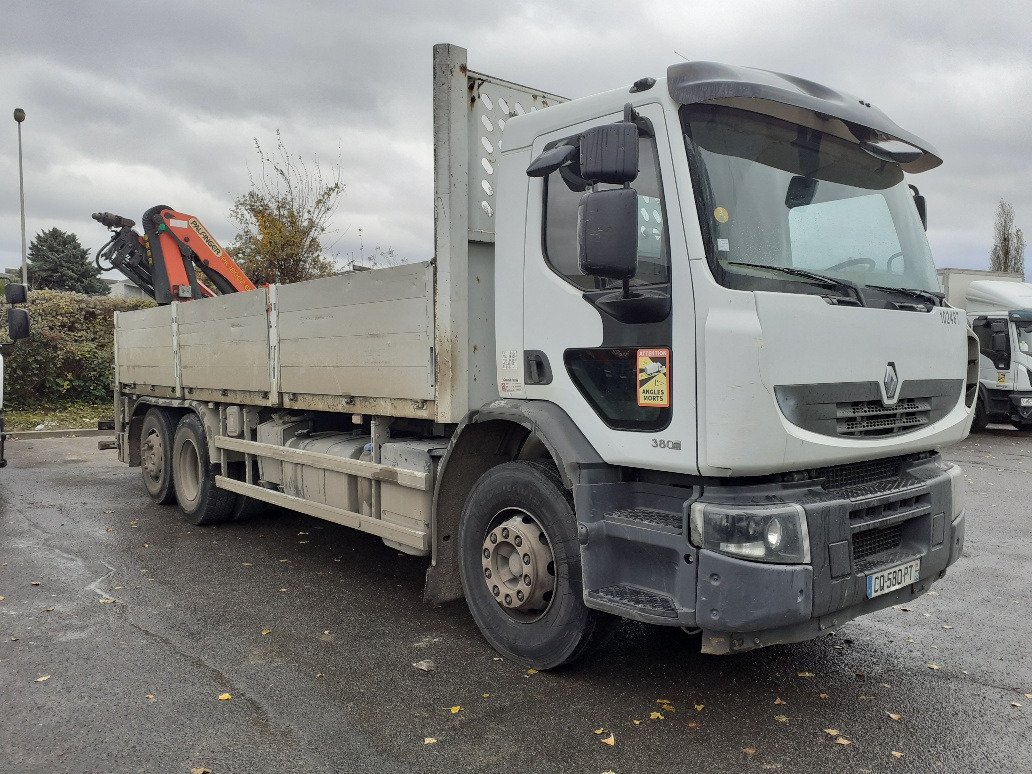 Biała ciężarówka Renault z zamontowanym dźwigiem Palfinger na skrzyni ładunkowej, widoczna na parkingu w pochmurny dzień.