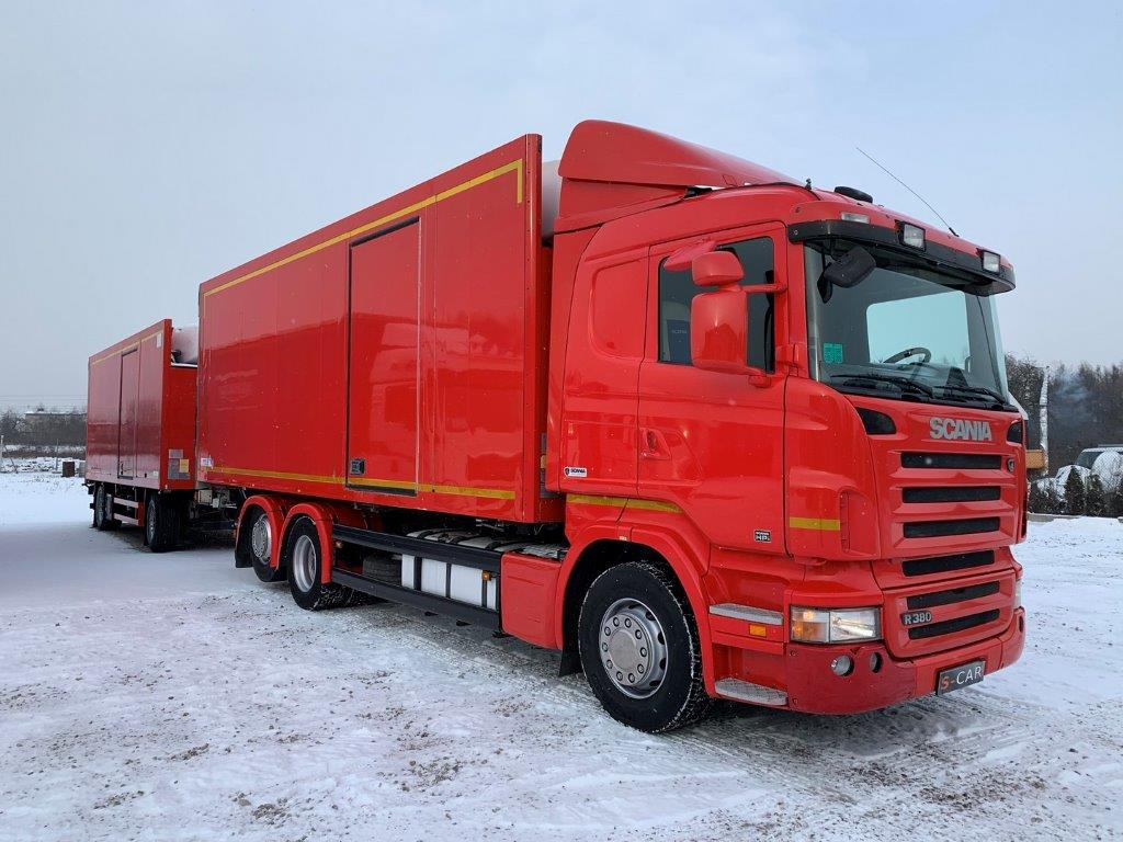 Czerwona ciężarówka Scania R380 z naczepą chłodniczą, zaparkowana na śniegu w pochmurny dzień.