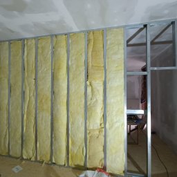 Dom-bud Serhii Varetskji - Konstrukcja ścianki działowej z metalowych profili wypełniona wełną mineralną. Widoczne instalacje, fragment podłogi i sufitu. Prace wykończeniowe w surowym wnętrzu.