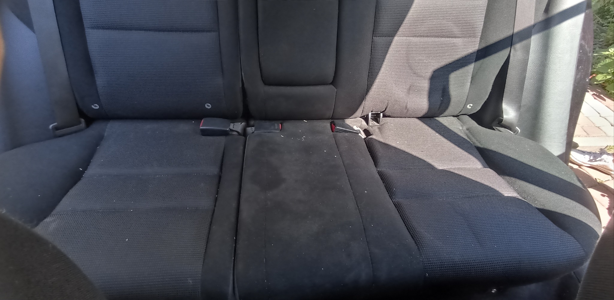 Zabrudzone, tekstylne siedzenie samochodowe z widocznymi plamami i okruchami przed czyszczeniem.