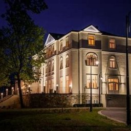 Tani Dom - Elegancki, trzypiętrowy budynek usługowy w stylu klasycystycznym, oświetlony nocą, z widocznymi detalami architektonicznymi i oświetleniem zewnętrznym.