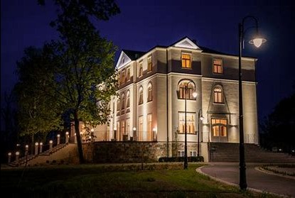 Elegancki, trzypiętrowy budynek usługowy w stylu klasycystycznym, oświetlony nocą, z widocznymi detalami architektonicznymi i oświetleniem zewnętrznym.