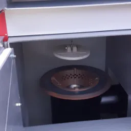 Wnętrze szarego pieca na paliwo stałe z widocznym rusztem i elementem regulującym dopływ powietrza na łańcuszku.