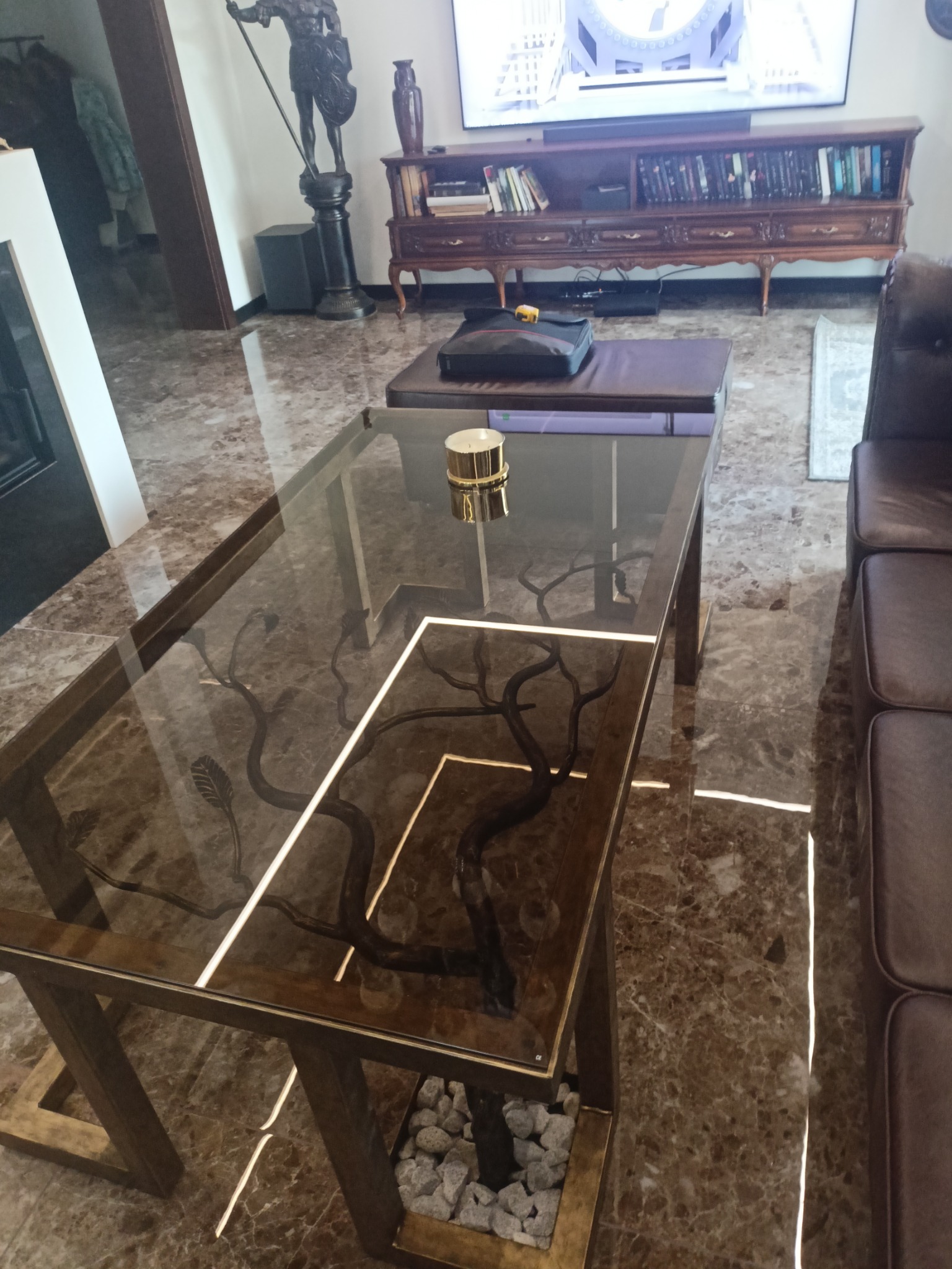 Stylowy stolik kawowy z szklanym blatem, pod którym umieszczono dekoracyjne gałęzie i kamienie, tworzące unikalną kompozycję.