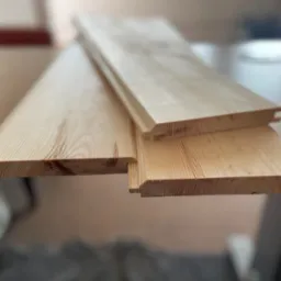 Drewniane panele boazeryjne z widocznymi profilami łączeniowymi, przygotowane do montażu przez stolarza z Pruszkowa.