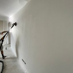 Freaky Painters - Szlifowanie ściany szlifierką z odkurzaczem, widoczne ślady po gładzi, szpachelka na podłodze, przygotowanie do malowania.