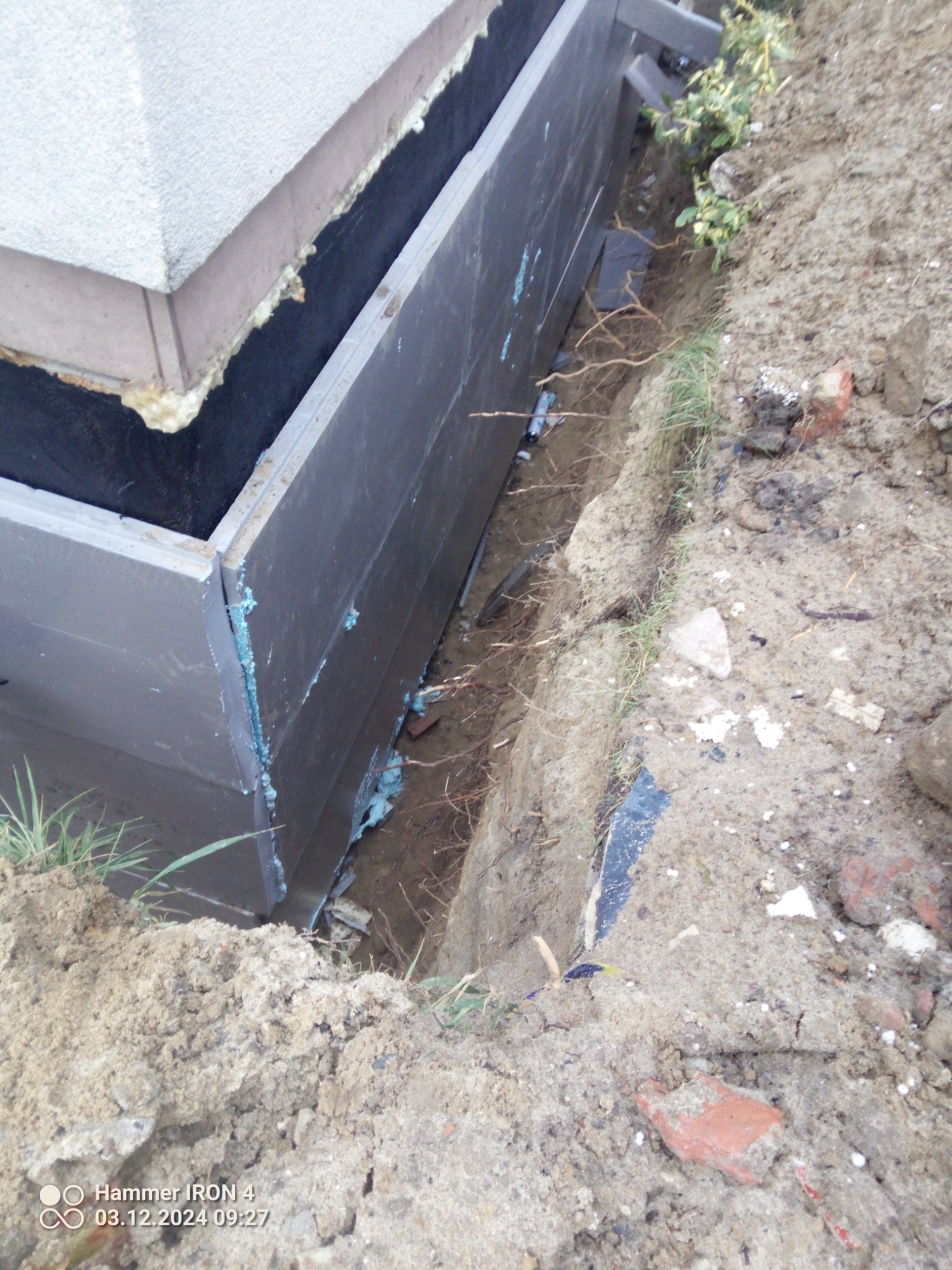 Fundament budynku zabezpieczony izolacją w wykopie w Zawadach. Widoczne detale łączeń i zabezpieczeń przeciwwilgociowych. Grunt ziemny.