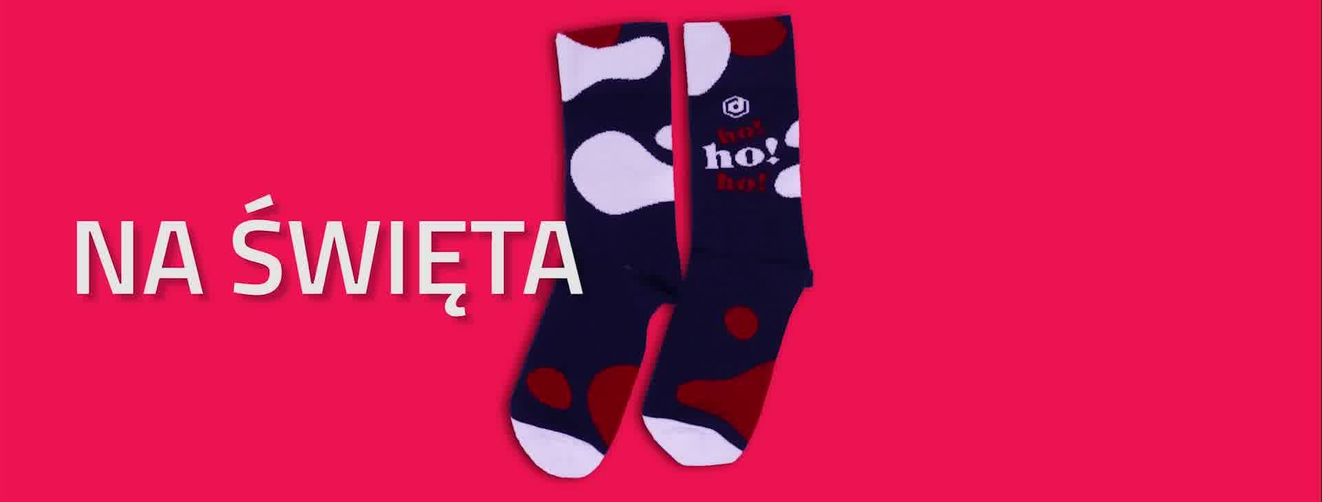 Dwie pary granatowych skarpet z białymi i czerwonymi wzorami, leżące na różowym tle z napisem 'NA ŚWIĘTA'.