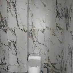 Wykończona łazienka z toaletą w stylu marmuru, białe płytki z szarymi i brązowymi żyłami na ścianach i podłodze, widoczne kartony po płytkach.