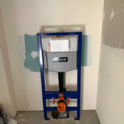 Stelaż podtynkowy WC marki Sanit, z widocznymi rurami, zamontowany w łazience w Radomiu. Ściany przygotowane do dalszych prac wykończeniowych.