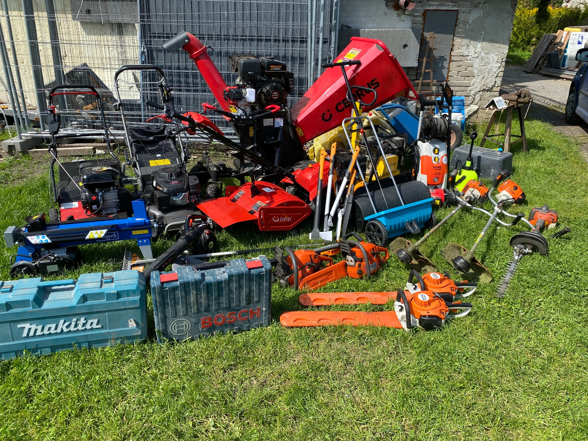 Zestaw różnorodnych narzędzi ogrodniczych i sprzętu do prac zewnętrznych, w tym kosiarki, glebogryzarki, piły łańcuchowe Husqvarna i Stihl, nożyce do żywopłotu, opryskiwacze, skrzynki narzędziowe...