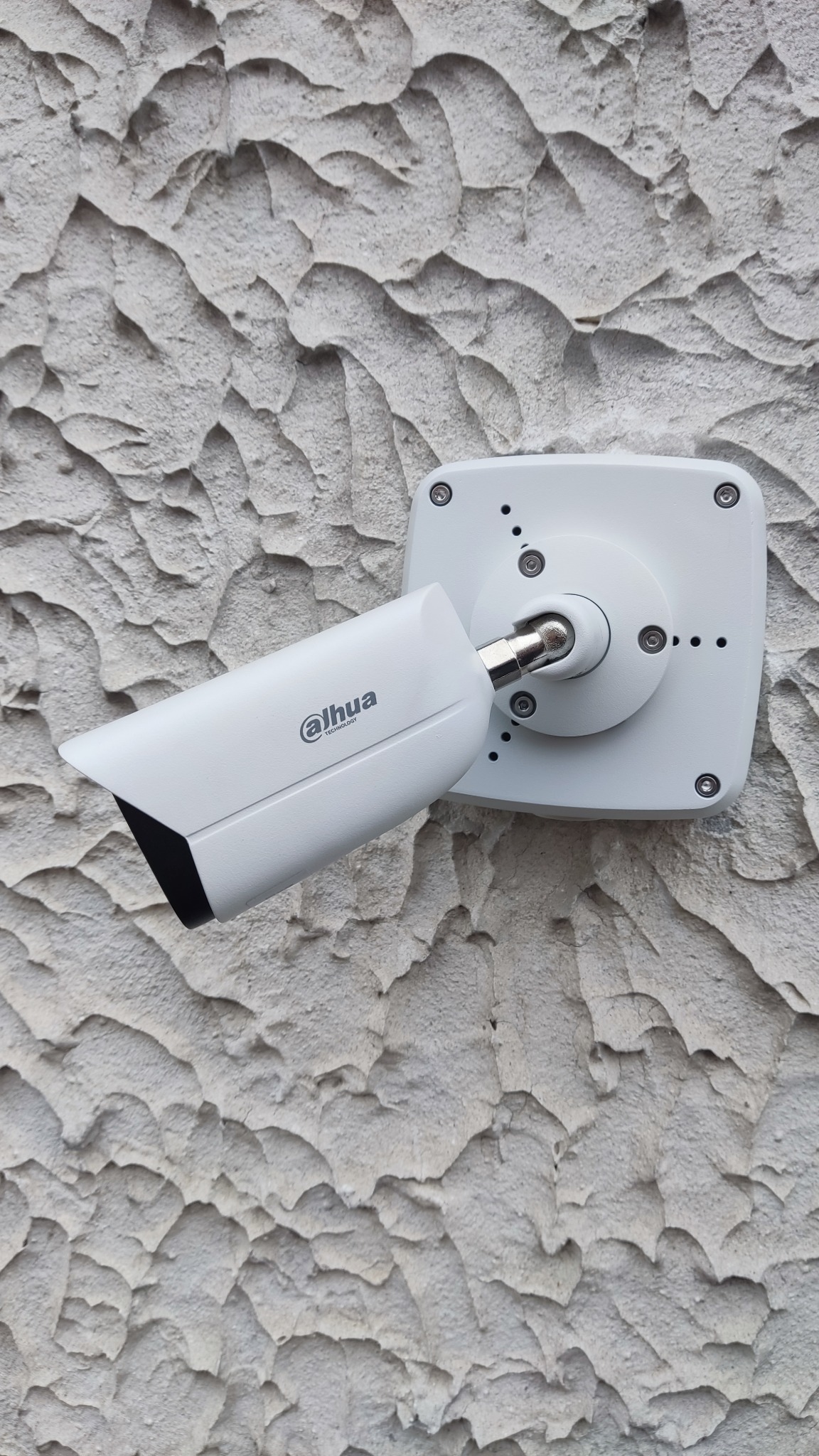 Kamera monitoringu Dahua zamontowana na chropowatej, jasnej ścianie budynku w Opolu Lubelskim, widok z dołu.
