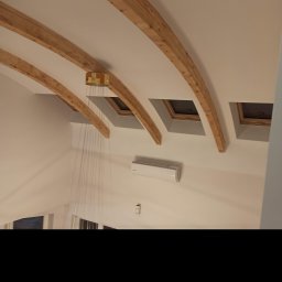 Usługi remontowo budowlane Kowalczyk Arkadiusz - Wysoki pokój z drewnianymi belkami stropowymi, oknami dachowymi i klimatyzacją na ścianie, widok z dołu