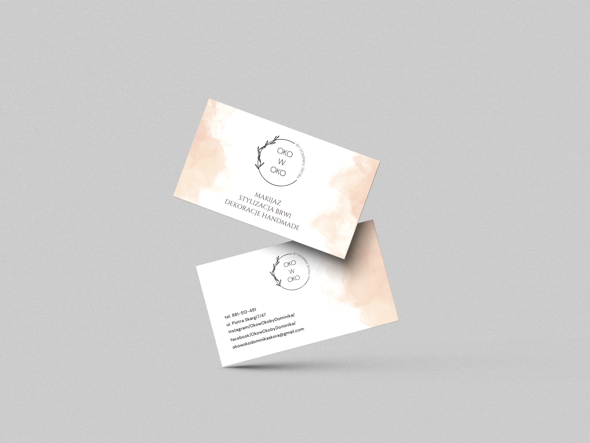 Dwie wizytówki z logo i informacjami kontaktowymi firmy Oko w Oko, specjalizującej się w makijażu, stylizacji brwi i dekoracjach handmade, na jasnoszarym tle.